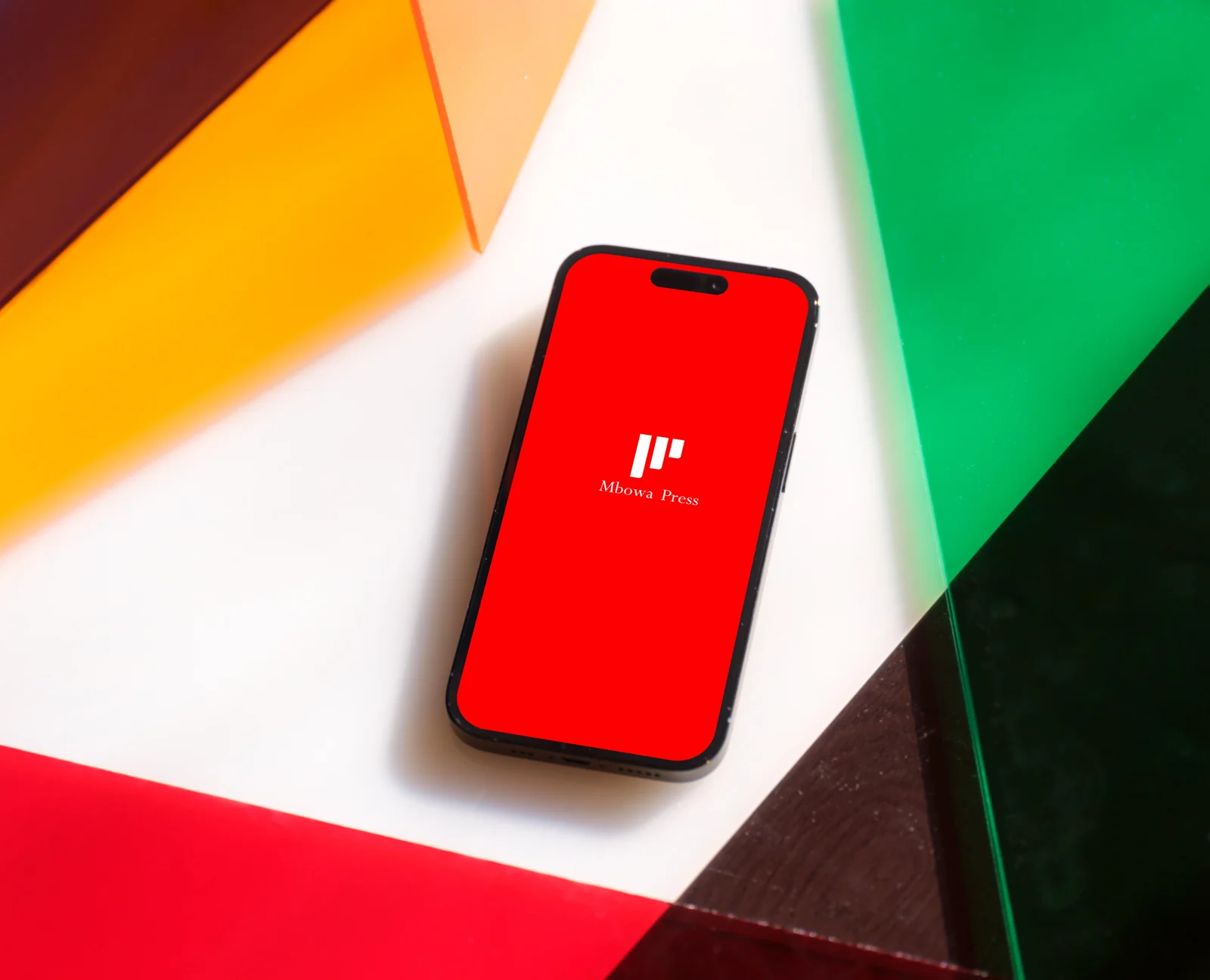 Mbowa Press logo on a red phone screen, among coloured acrylic panels